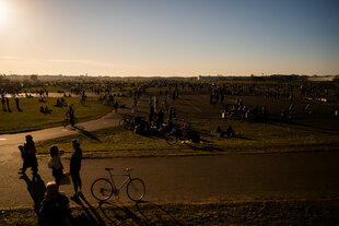 Menschen genießen die untergehende Sonne auf dem Tempelhofer Feld.