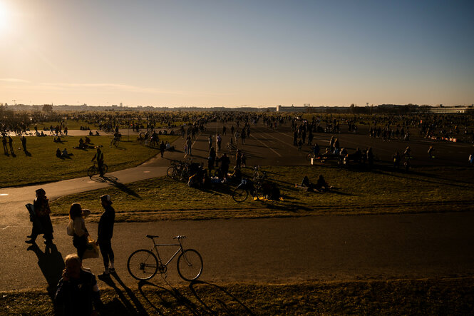 Menschen genießen die untergehende Sonne auf dem Tempelhofer Feld.