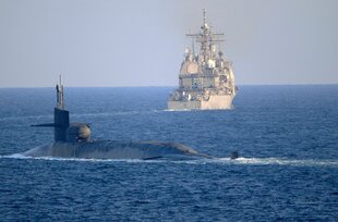 Ein U-Boot vor einem Kreuzer im Meer