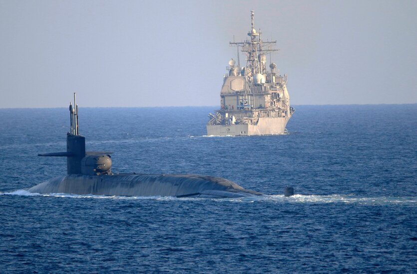 Ein U-Boot vor einem Kreuzer im Meer