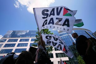 Eine Frau schwenkt eine Fahne mit der aufschirft: Save Gaza vor dem Gebäude des Europäischen Rats in Brüssel