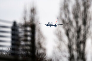 Ein Flugzeug hinter schemenhaften Bäumen im Anflug auf Hannover
