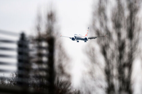 Ein Flugzeug hinter schemenhaften Bäumen im Anflug auf Hannover