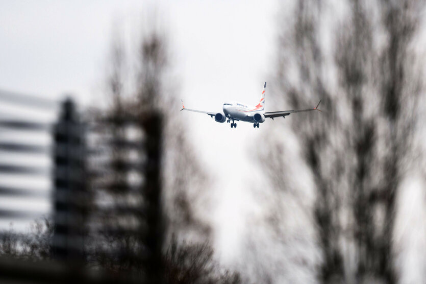 Ein Flugzeug hinter schemenhaften Bäumen im Anflug auf Hannover