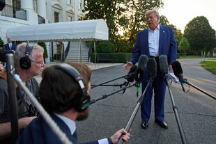 Reporter halten Donald Trump Mikros hin, während der spricht