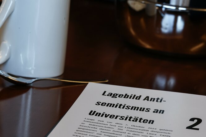 Eine aufgeschlagene Magazinseite mit der Überschrift "Lagebild Antisemitismus an Universität" liegt auf einem Tisch.