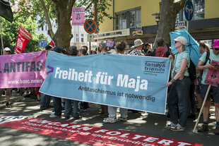 Eine Gruppe von Menschen auf einer Straße trägt ein großes blaues Banner mit der Aufschrift 