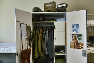 Blick in den geöffneten Spind eines bundeswehrsoldaten, zu sehen sind Uniform-Jacken, Taschen, und das obligatorische Pin-Up Foto an der Schranktür