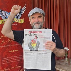 Porträt eines Mannes mit geballter hochgestreckter Faust, Baskenmütze und Zeitung in der Hand