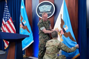 Zwei Soldaten richten die Flagge des Vorsitzenden der Joint Chiefs auf der Bühne im Pentagon auf
