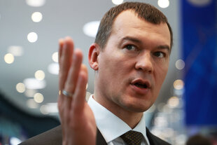 Michail Degtjarjow schaut in Kamera hebt rechte Hand