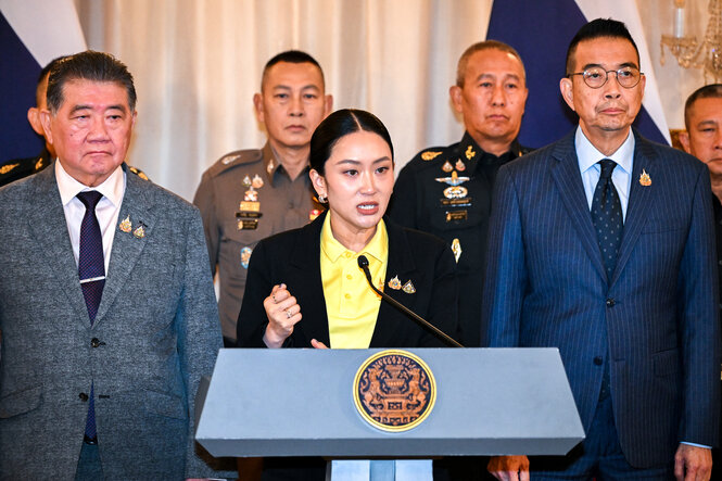 Thailand Premierministerin Paetongtarn Shinawatra steht an einem Pult, hinter ihr mehrere Menschen in Anzügen. Sie ballt die Faust.