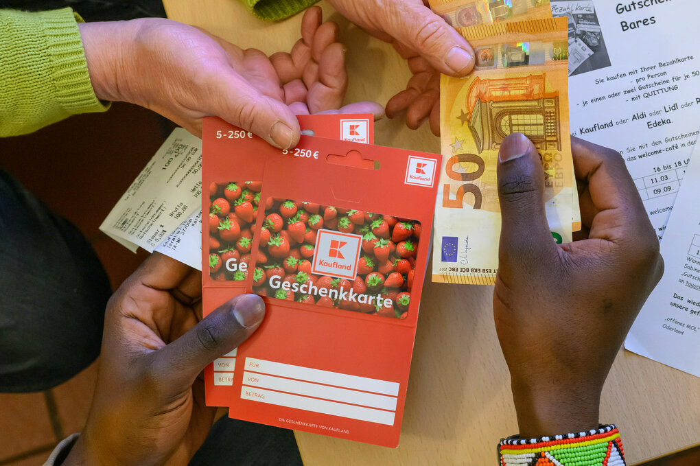 Ein junger Mann aus Afrika tauscht Gutscheine gegen Bargeld