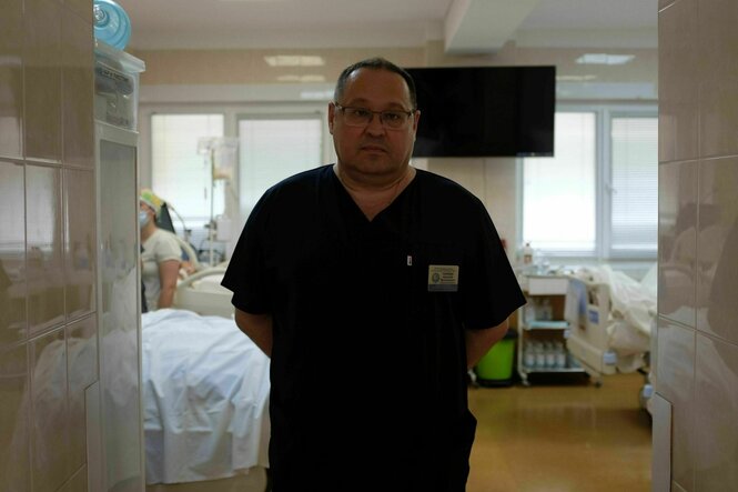 Ein Arzt im schwarzen Kittel steht im Flur eines Krankenhauses