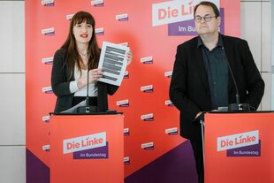 Heidi Reichinnek zeigt die vollständig geschwärzten Seiten des Berichts über den Maskendeal von Jens Spahn - neben ihr steht Sören Pellmann
