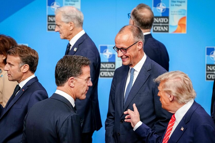 Männer beim Natogipfel: Macron am Rand, Mark Rutte lauscht Donald Trump, der zeigt mit dem Finger auf einen lächelnden Merz
