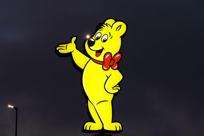 Ein gelbes Haribo-Gummibärchen leuchtet als Reklamefigur in der Dunkelheit