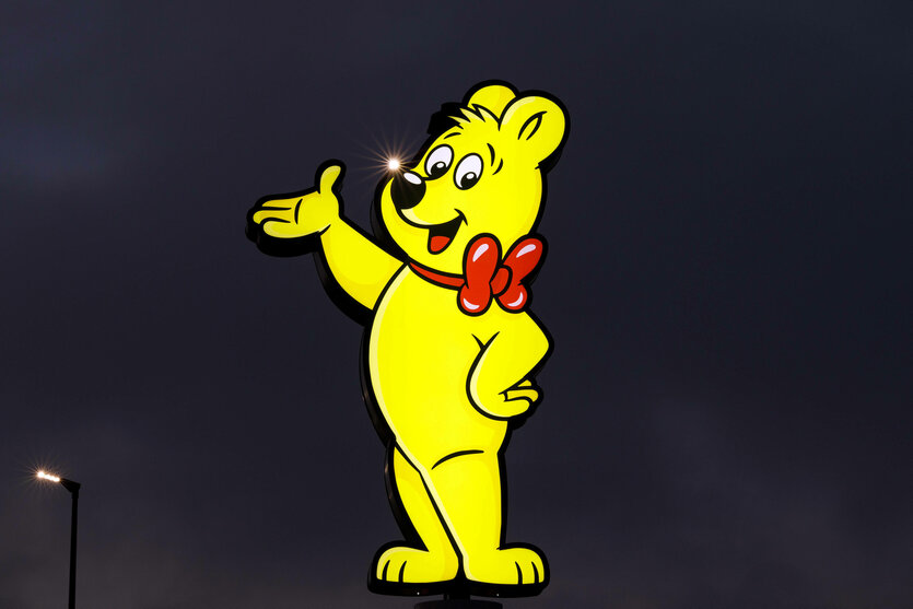 Ein gelbes Haribo-Gummibärchen leuchtet als Reklamefigur in der Dunkelheit