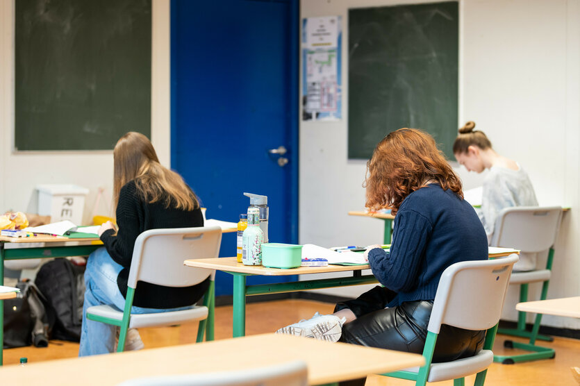 Schüler sitzen am Tisch und schreiben eine Klassenarbeit.