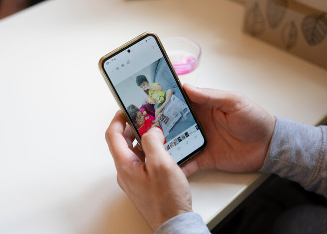 Wael Aljasim schaut auf sein Smartphone, auf dem er Fotos seiner Kinder gespeichert hat