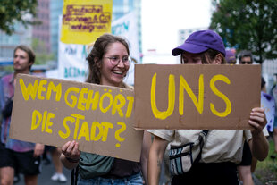 Demonstrant*innen mit Schildern: 1. Wem gehört die Stadt ? 2. UNS