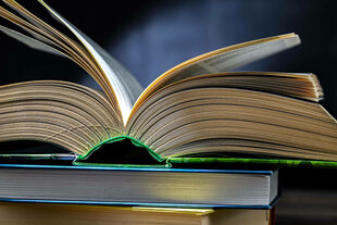 Ein aufgeschlagenes Buch, das auf einem Stapel anderer Bücher liegt