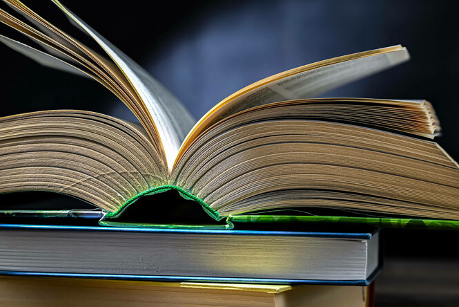 Ein aufgeschlagenes Buch, das auf einem Stapel anderer Bücher liegt
