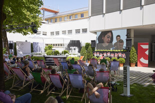 Leute in Liegestühlen vor einer Leinwand