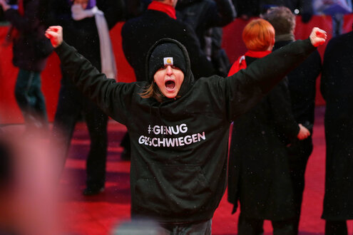 Demonstrantin in schwarz auf einem roten Teppich, Aufschrift auf dem Sweatshirt "#Genug Geschwiegen"