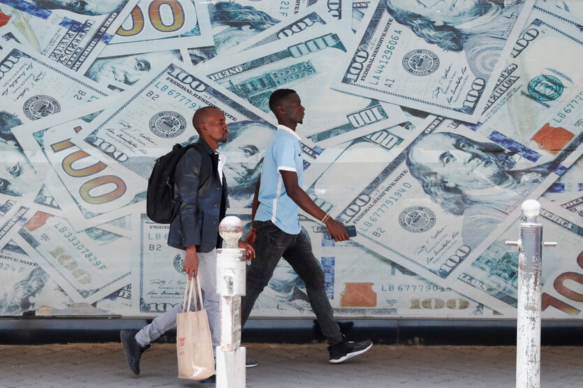 Vor einer Wechselstube in der Innenstadt von Nairobi laufen Menschen an einem Bild von US-Dollar-Scheinen vorbei