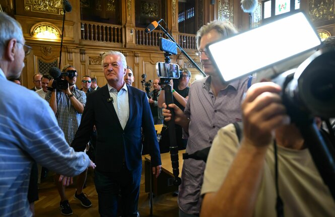 Ein Mann ist umringt von Vertretern der Presse
