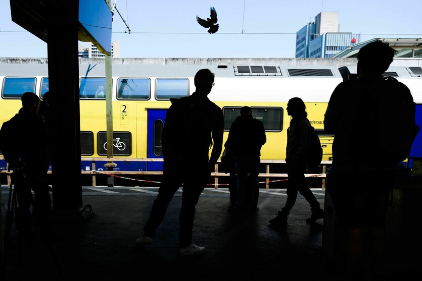 Die Silhouetten von Fahrgästen zeichnen sich am Hauptbahnhof Hannover vor einem Regionalzug ab