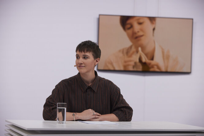 Eine Frau mit kurzen Haaren sitzt an einem Tisch