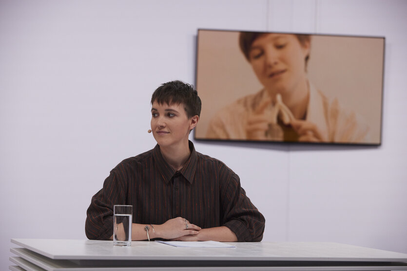 Eine Frau mit kurzen Haaren sitzt an einem Tisch