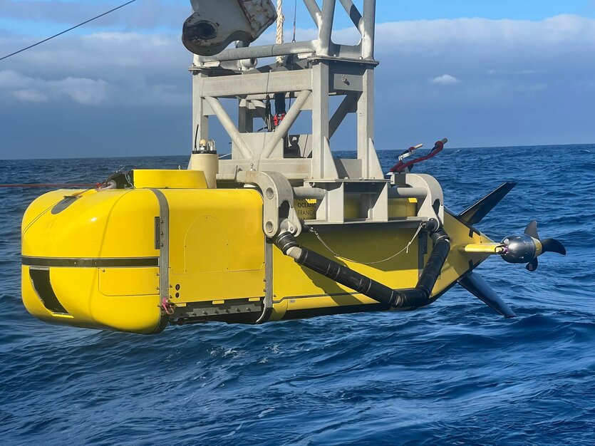 Ein gelber Tauchroboter wird mit einem Kran ins Meer gelassen