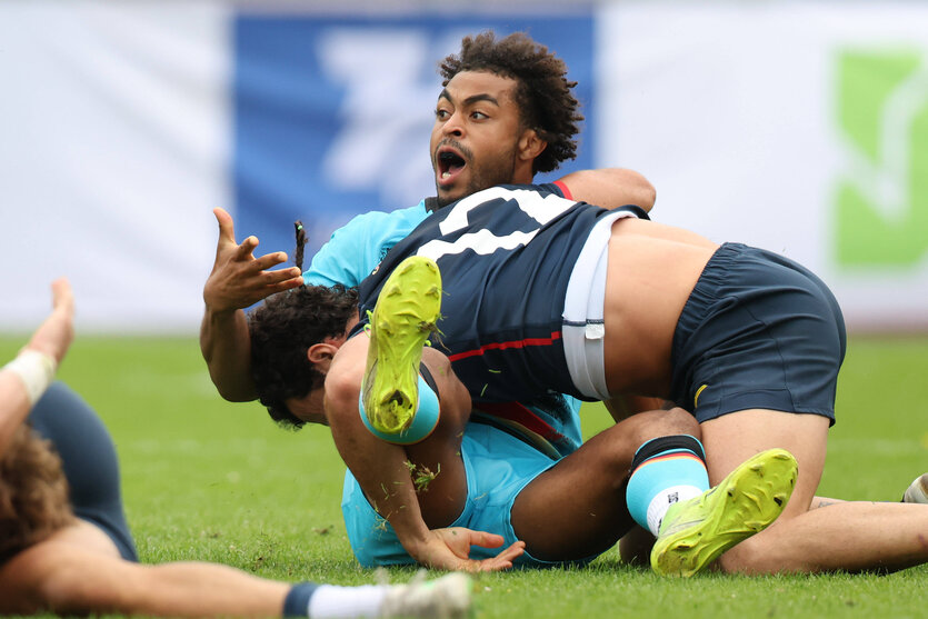Ein Sportler liegt unter einem Gegenspieler und macht eine Beschwerde-Geste