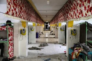 Zellengang im Gefängnis, kaputte Telefone, Schutt und Klamotten auf dem Boden
