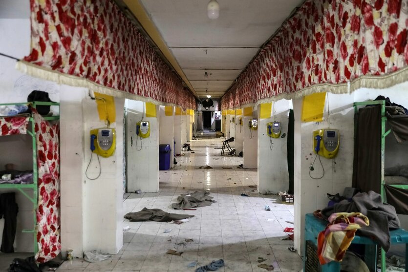 Zellengang im Gefängnis, kaputte Telefone, Schutt und Klamotten auf dem Boden
