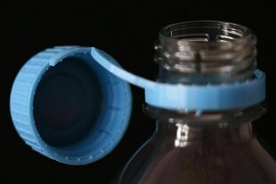 Plastikflasche mit fest an der Flasche verbundenen blauen Deckel