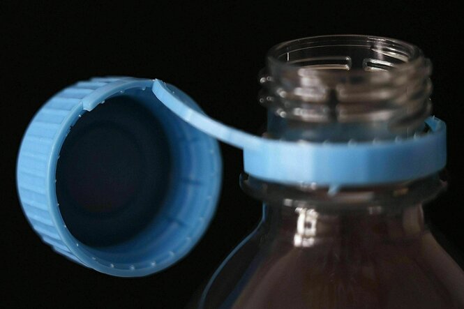 Plastikflasche mit fest an der Flasche verbundenen blauen Deckel