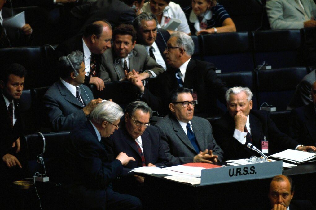 Die sowjetische Delegation sitzt in der ersten Reihe - Breschnejew lässt sich von einem Mann etwas erklären, der Aussenminister Andrey Gromyko mit kritischem Blick, die Männer in den hinteren Reihen diskutieren angeregt