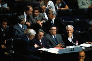 Die sowjetische Delegation sitzt in der ersten Reihe - Breschnejew lässt sich von einem Mann etwas erklären, der Aussenminister Andrey Gromyko mit kritischem Blick, die Männer in den hinteren Reihen diskutieren angeregt