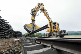 Arbeiter zerlegen mit einem Bagger alte Bahnschienen während der Sanierung einer ICE-Trasse.