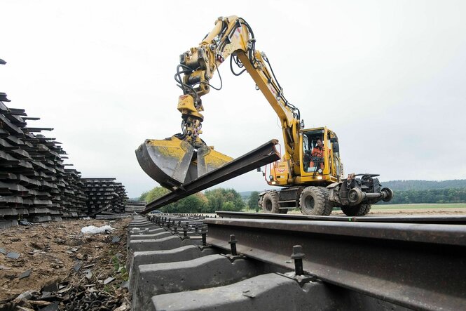Arbeiter zerlegen mit einem Bagger alte Bahnschienen während der Sanierung einer ICE-Trasse.