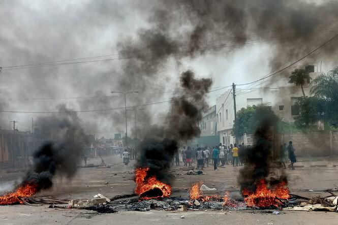 Auf einer Straße brennen drei Feuer, die von Protestierenden entzündet wurden. Im Hintergrund sind Menschen zu sehen, die auf der Straße stehen