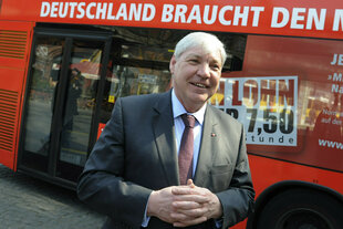 Vor einem Bus der Berliner Verkehrsbetriebe mit der Aufschrift "Deutschland braucht den Mindestlohn" steht der DGB-Vorsitzende Michael Sommer