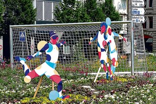 Bunte Statuen von Fußballspielerinnen auf einem Kreisverkehr