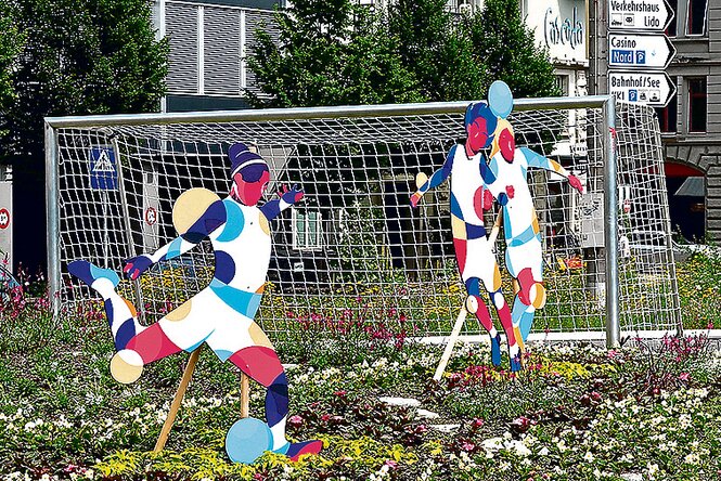 Bunte Statuen von Fußballspielerinnen auf einem Kreisverkehr