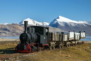 Eine historische Lok mit Kohleloren vor dem Panorama Spitzbergens