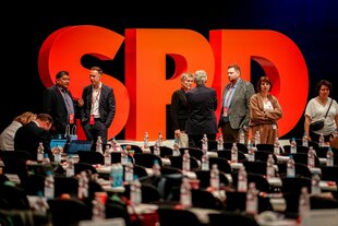 Delegierte stehen vor einem großen SPD Logo auf dem Bundesparteitag